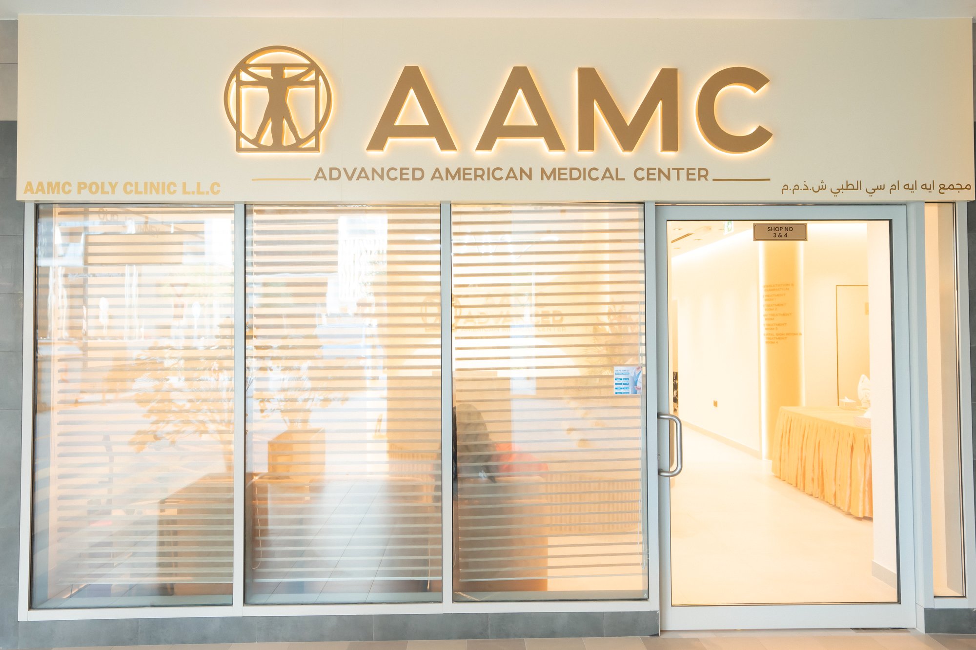Entrance to AAMC Polyclinic at Shops 03 and 04, Elite Business Bay Residence, showing the AAMC signage above glass doors.