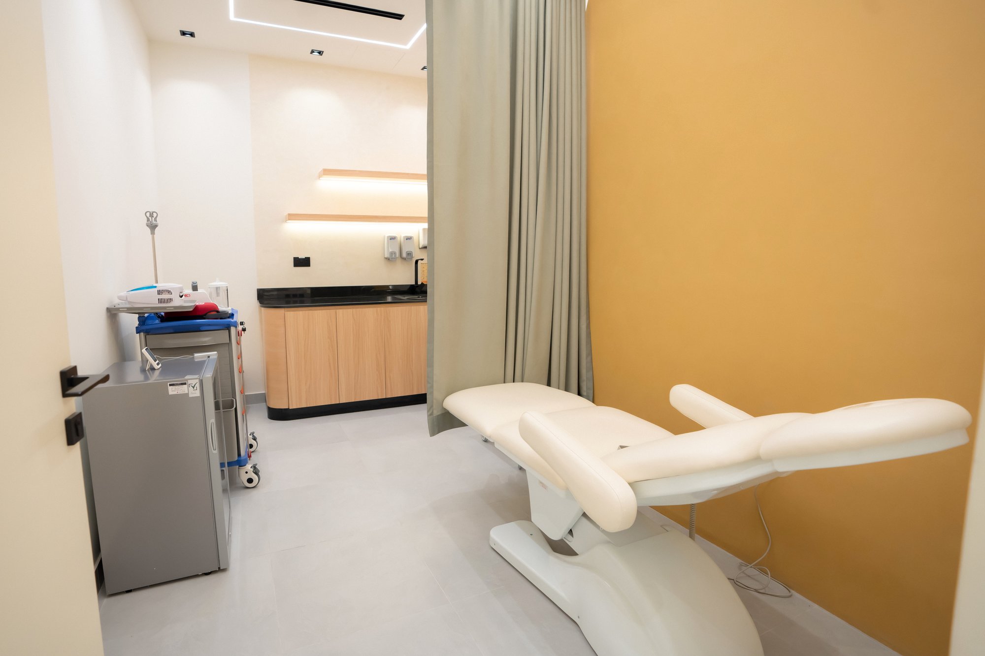 A private treatment room at AAMC Polyclinic with a reclining treatment chair, sink and clinical trolley.