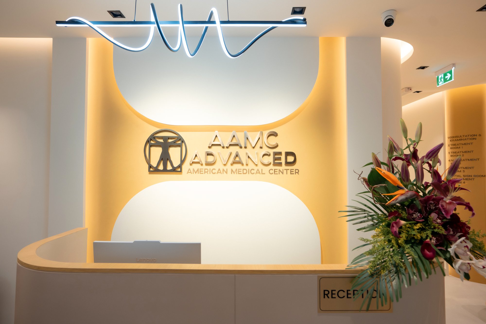 Reception desk at AAMC Polyclinic in Business Bay, with the clinic's illuminated gold signage on the wall behind it.